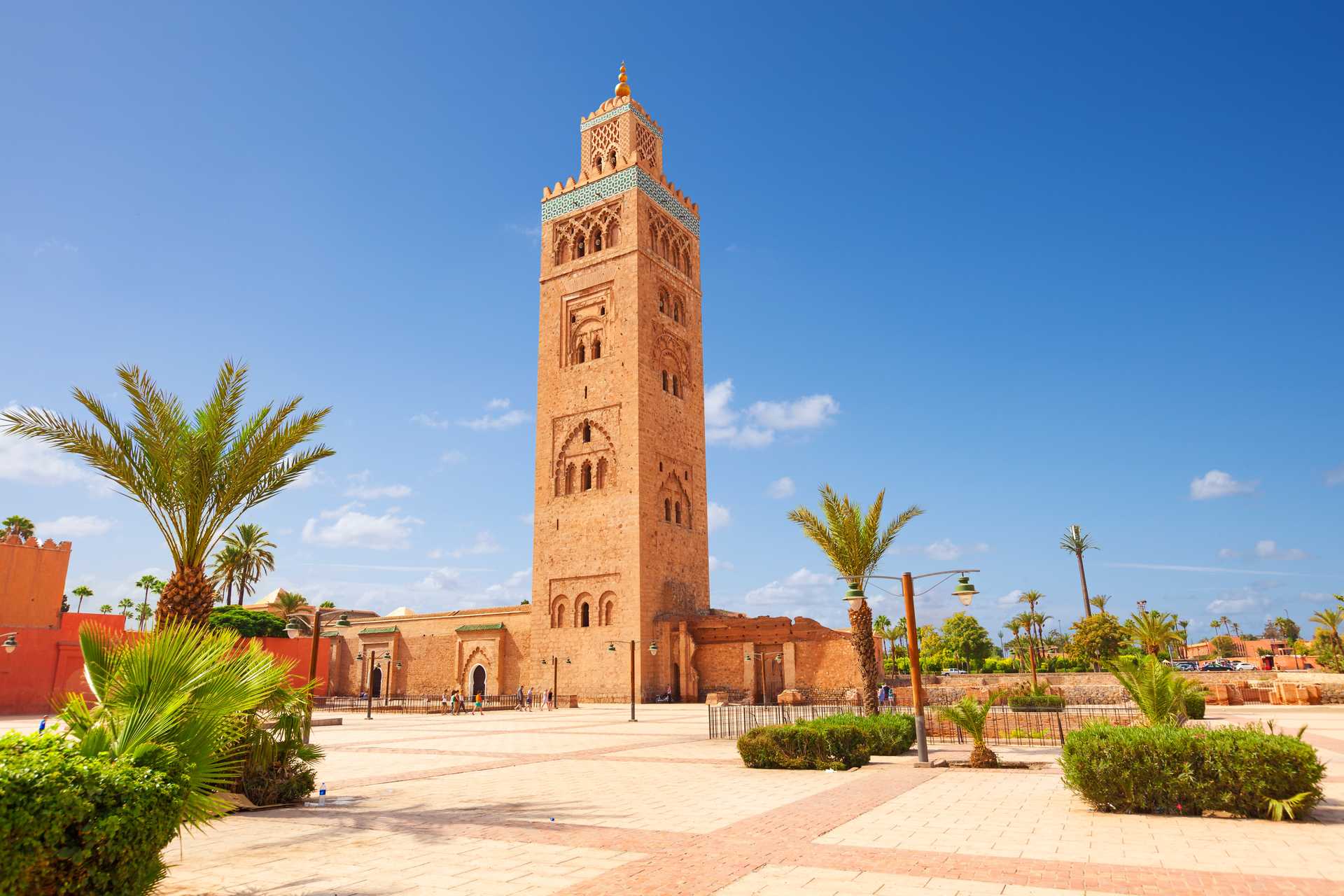 Minaret mešity Kutubíja v Marakéši s palmami a záhradami pod modrou oblohou